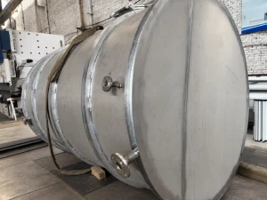 Fabricated stainless steel tank resting horizontally in the workshop, with nozzles and external rings