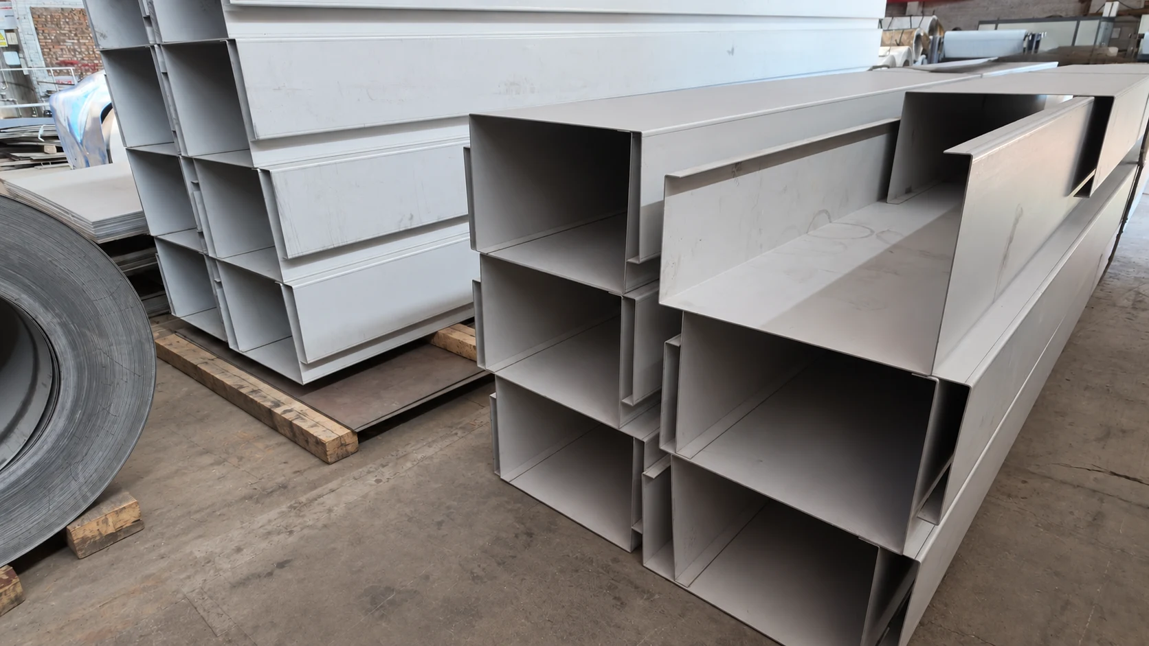 Long folded gutter sections with visible edge returns in a workshop